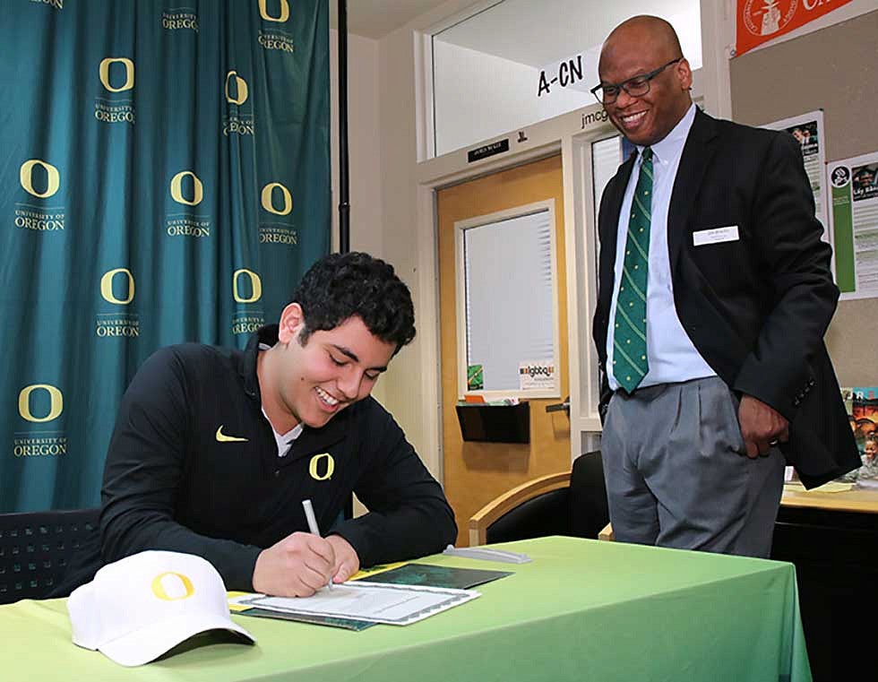Amahn Enayati signing his Stamps Scholarship with Associate Vice President Jim Brooks looking on Amahn Enayati signing his Stamps Scholarship with Associate Vice President Jim Brooks looking on