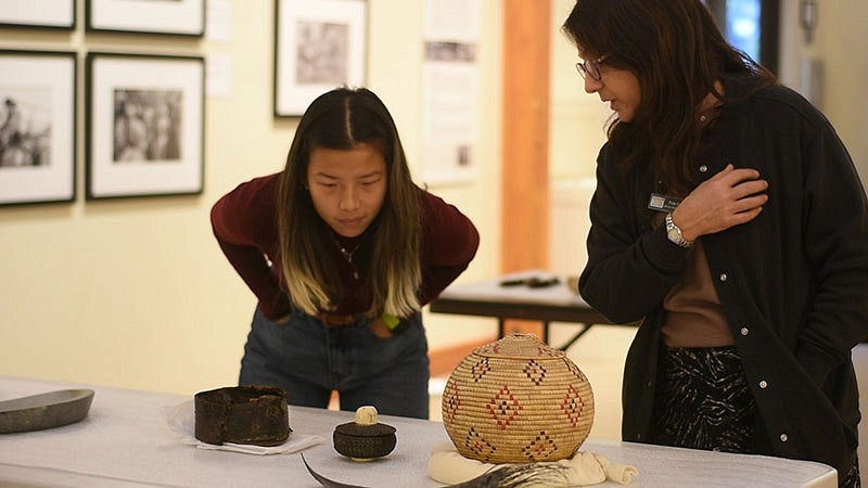 Students in Lisa Munger's class looking at pottery on a table