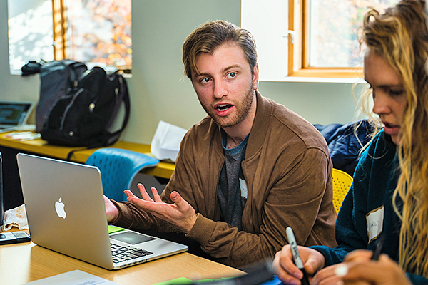 a student at a laptop asks a question in class