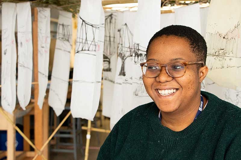 Neo Lehoko in front of paper drawings of a bridge