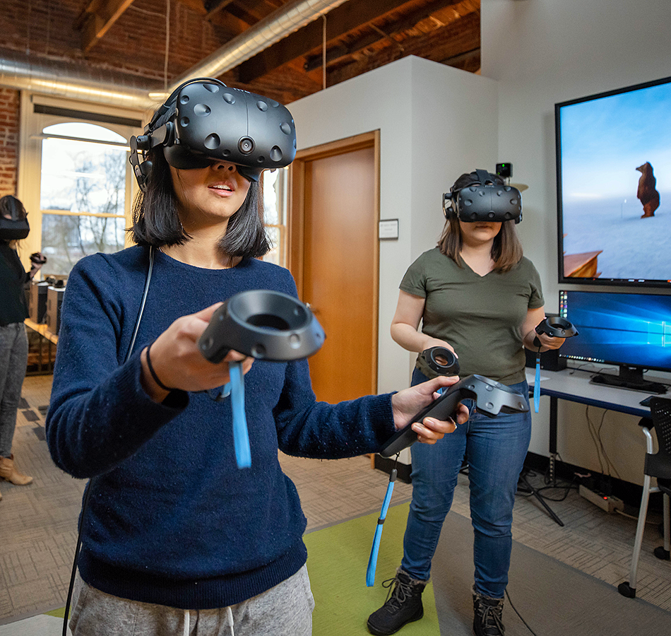 two students wearing VR headsets and holding controls in the OR Lab