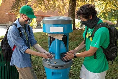 People wearing masks while washing their hands