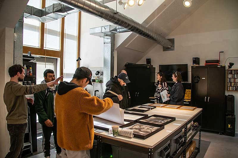 Small groups of people talking and looking at artwork on a table