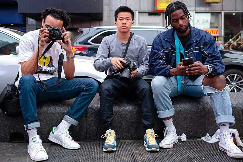 UO SOJC students Scotty Williams II, Ryan Hus, Duane Harris sitting on a curb with camera equipment