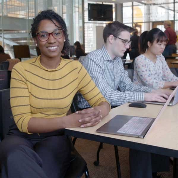Kristina Moyer with two students working on computers behind her