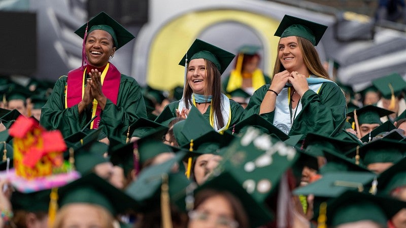 three women grads stand up