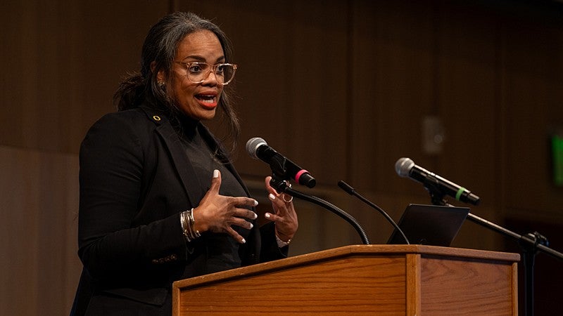 Lesley-Anne Pittard speaks at podium in ballroom