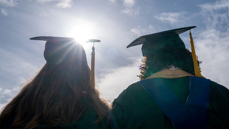 Graduates silhouetted in a sunset