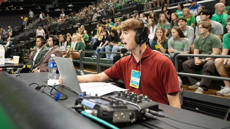 UO student Brody Napier calling a UO women's volleyball game