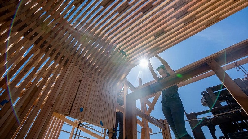 A student works on the frame of a structure that will help houseless people