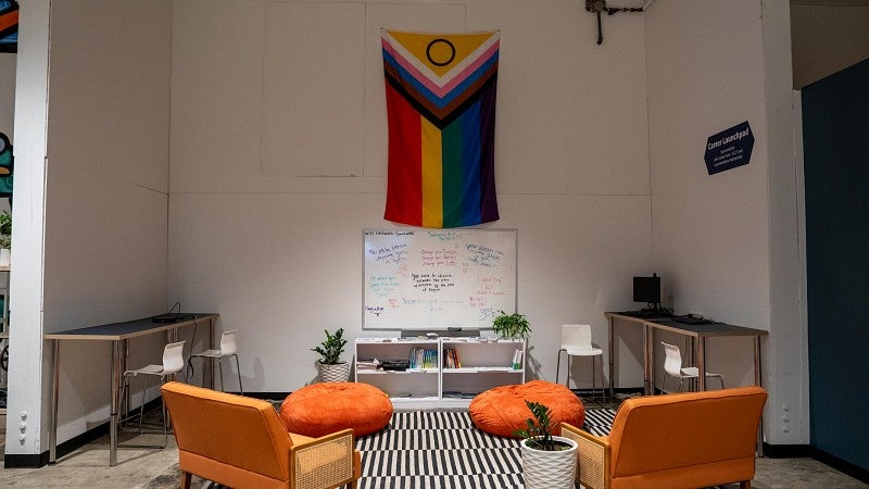 A cozy nook with orange couches, books and a computer where youth receive career support at a nonprofit that serves them.