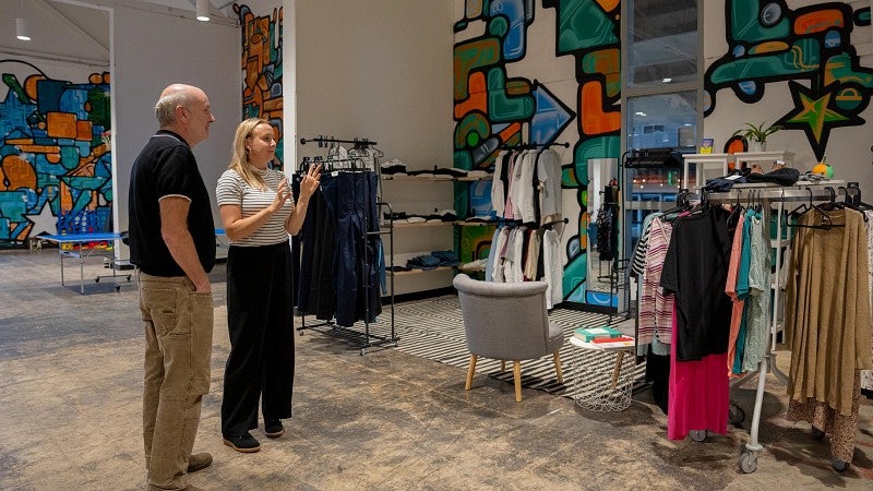 A man and woman look at clothing on a rack that are available free to youth at a nonprofit that serves youth.