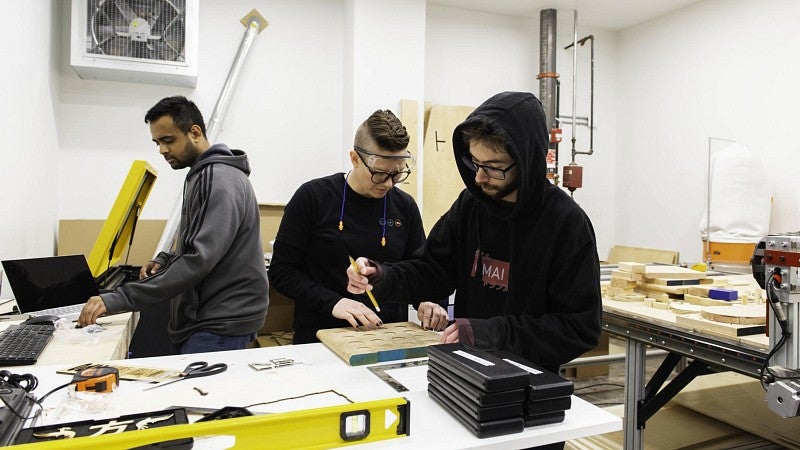 A young man uses a laser engraving machine at a nonprofit that serves youth.