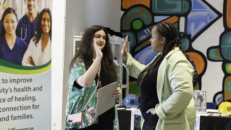 A youth intern high fives an adult after completing a summer learning experience.