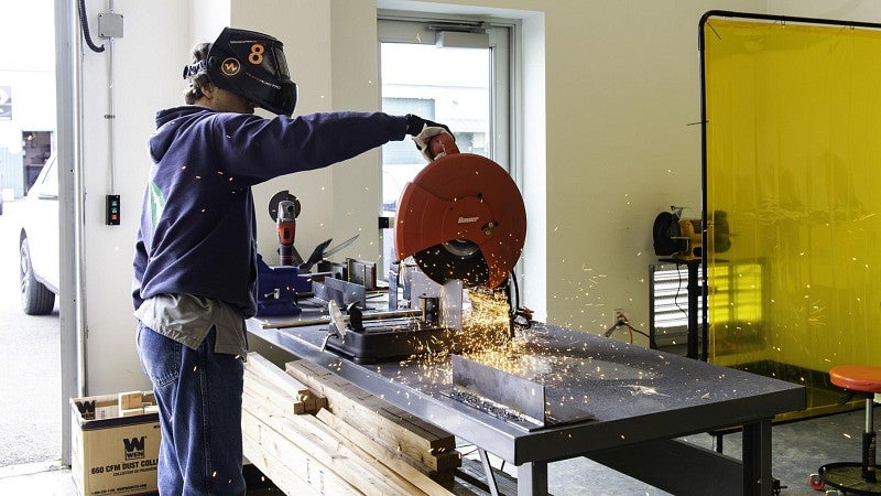 A young man fabricates metal in a manufacturing training program for youth.