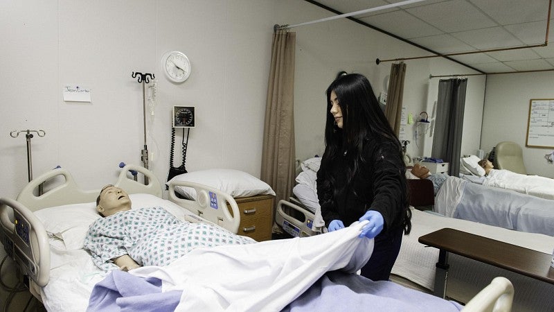 A young woman learns about patient care in a health care careers training program.