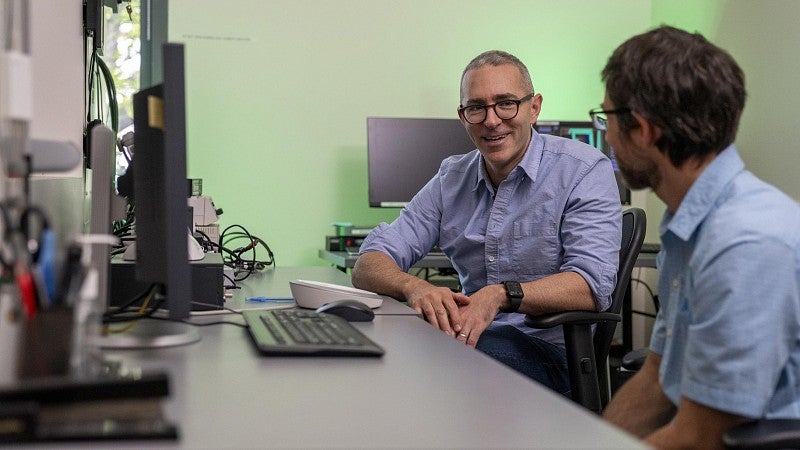 Brice Kuhl talking with another researcher in a lab