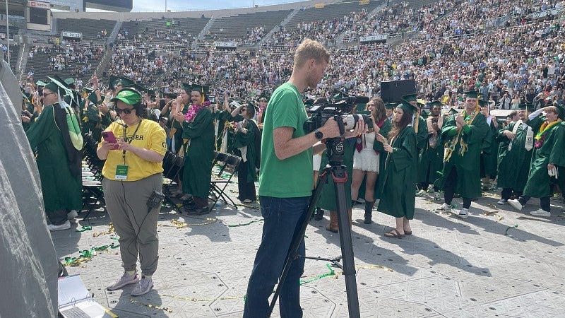 UO employees working at commencement with graduates in the background
