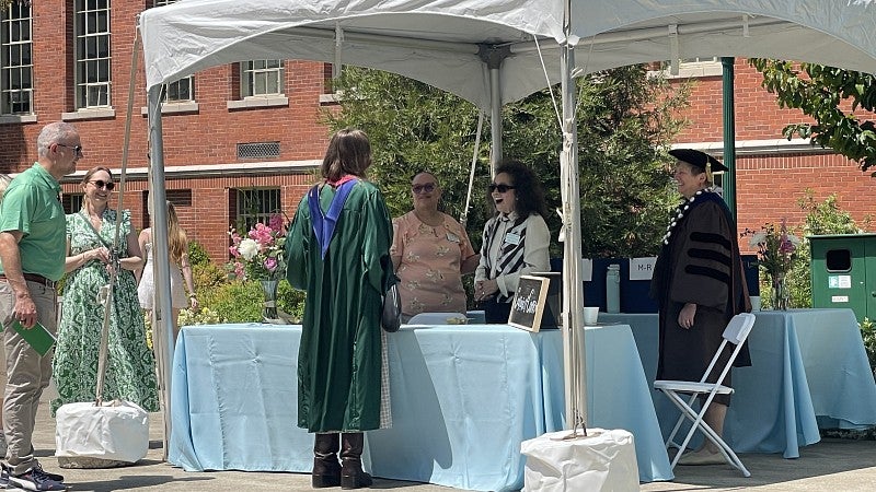 Clark Honors College employees congratulate a graduate under a tent at a reception