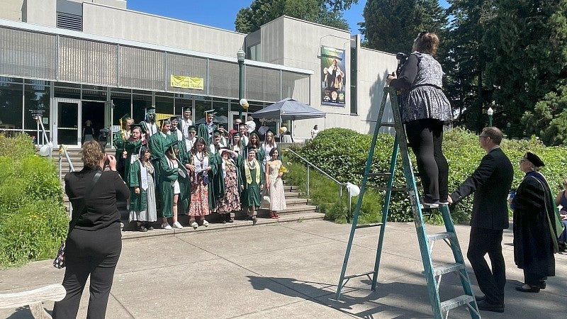 Photographers and department employees capture a class photo of UO graduates