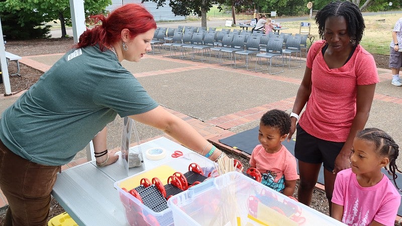 A museum educator helps a family get set up with a toy car activity about renewable energy