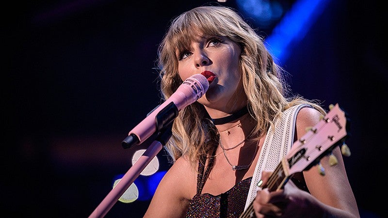 Woman holding guitar sings into microphone
