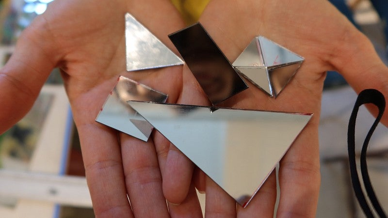 Pieces of reflective mirror are displayed in a woman's open hands