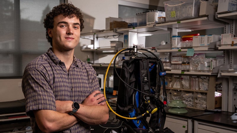 Student posing next to scuba gear