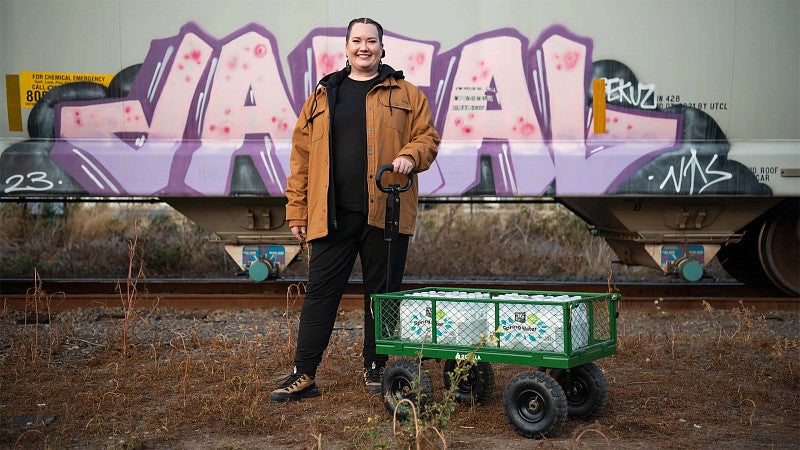 Woman with a wagon in front of a graffiti-covered wall