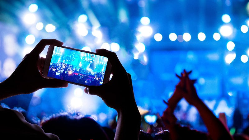 Person holding up a phone camera at a concert