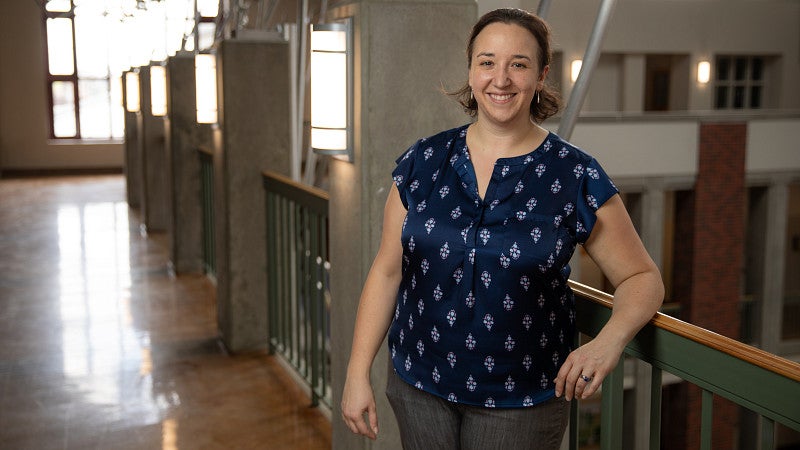 A woman stands against a bannister in a building