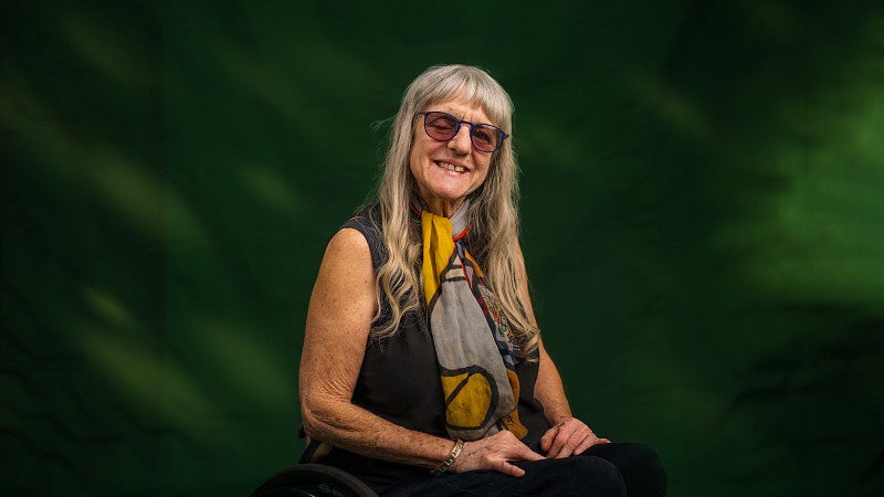 Studio portrait of Susan Sygall against green backdrop