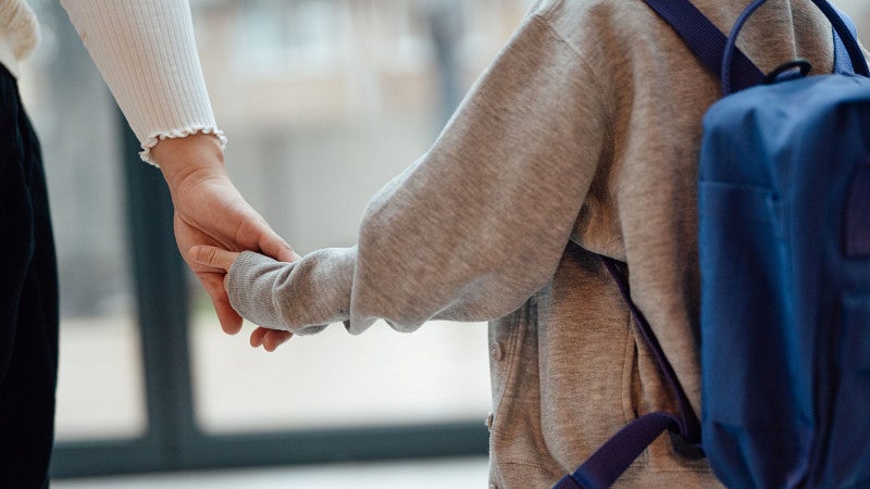 A child holds hands with an older person