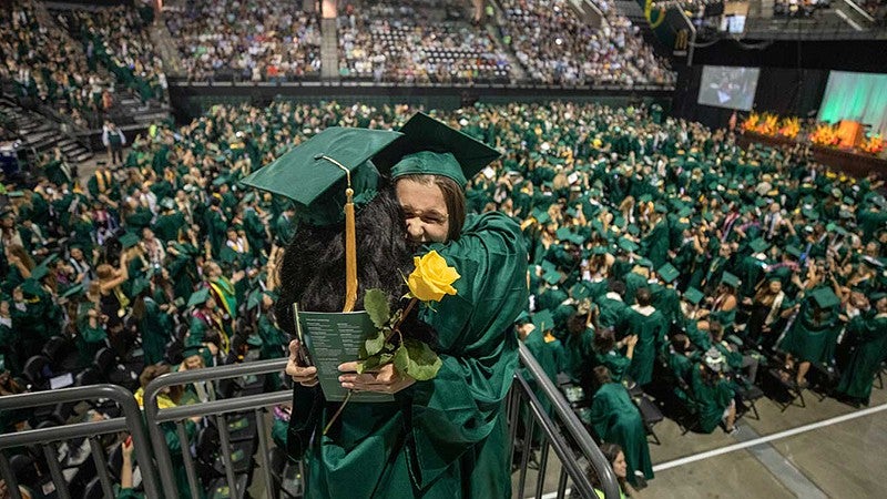 Two graduates hugging during 2019 commencement