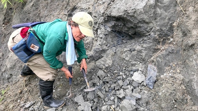 Woman with pick-axes bagging mineral samples.