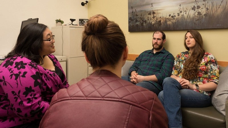 A couple on a couch talking with two counselors