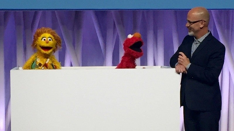 Phil Fisher interacting with a muppet during a conference presentation