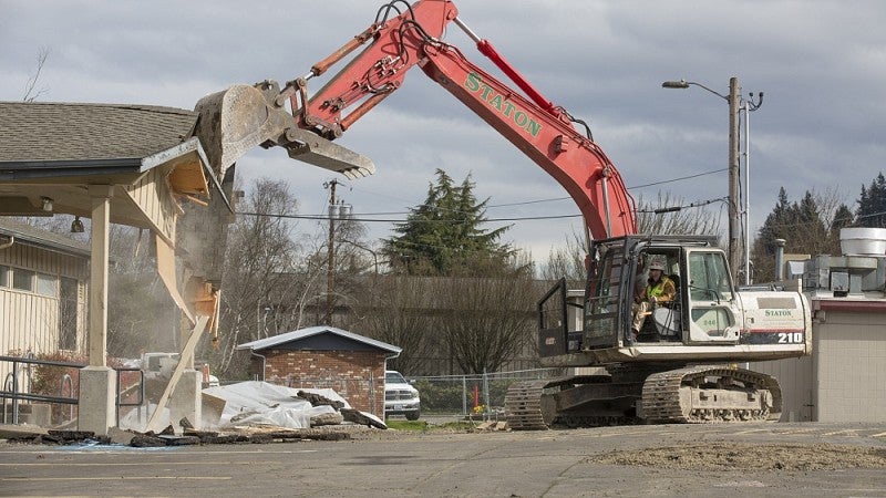 Backhoe tearing down building