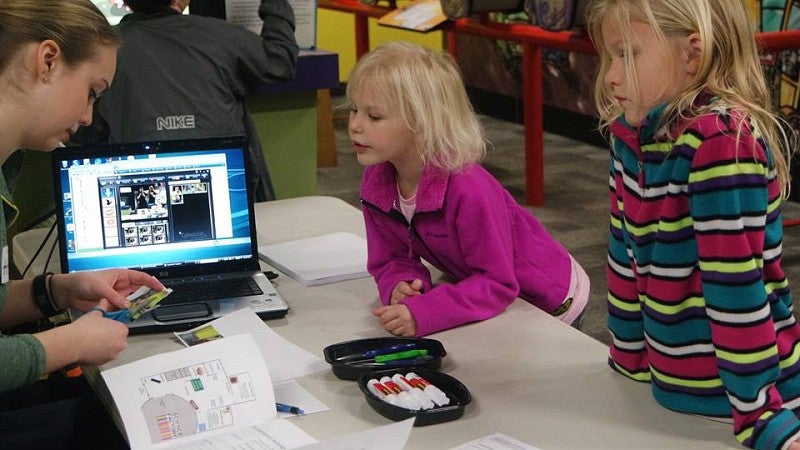 Children at an activity table with a UO student