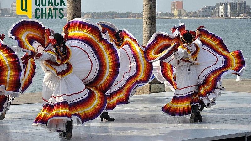 Image shows Mexican folklore dancers moving about in Jalisco