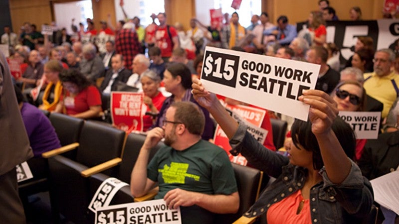 People holding signs at a Seattle meeting on the minimum wage