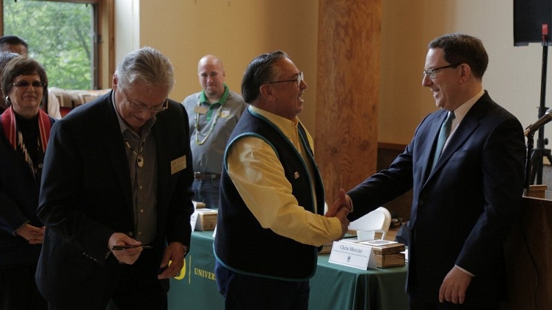 Reyn Leno of the Confederated Tribes of Grande Ronde shakes hands with UO President Michael Schill