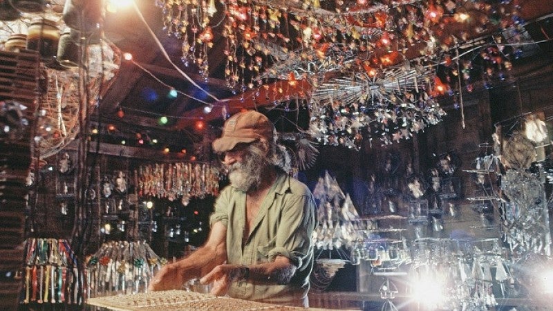 Emery Blagdon with his “healing machine” constructions and a stack of circuit board paintings inside the shed on his farm, Garfield Table, Nebraska. Photograph 1979, Sally and Richard Greenhill. 