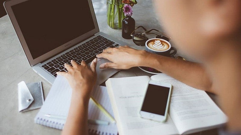 Woman's hands working with laptop, notebooks