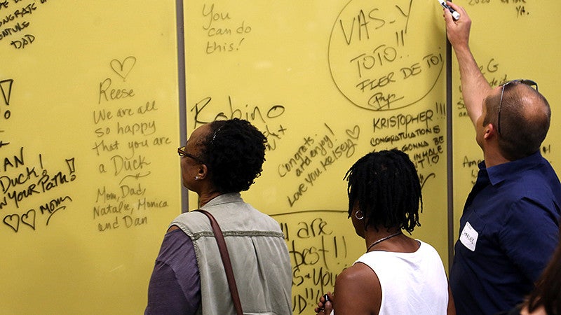 Parents write encouraging greetings on a glass wall