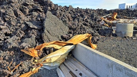 Lava stretches across a road, leaving debris behind