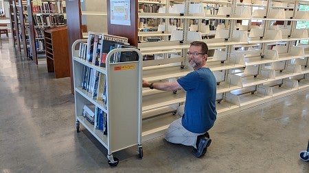 Michael Brown shelves books in the UO Portland Library.