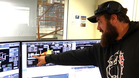 A man gestures at a computer monitor displaying information about power-generation equipment