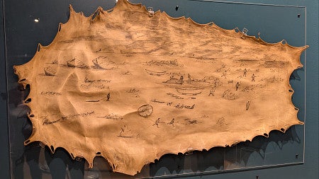 A seal skin shows images of people and animals in a watery setting