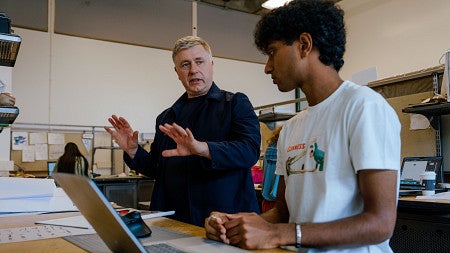 An architect gestures with his hands to explain a concept to a student